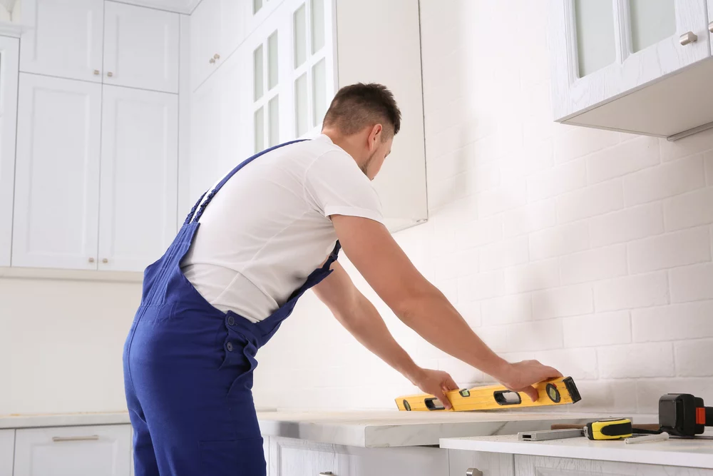 Worker,measuring,countertop,with,spirit,level,in,kitchen